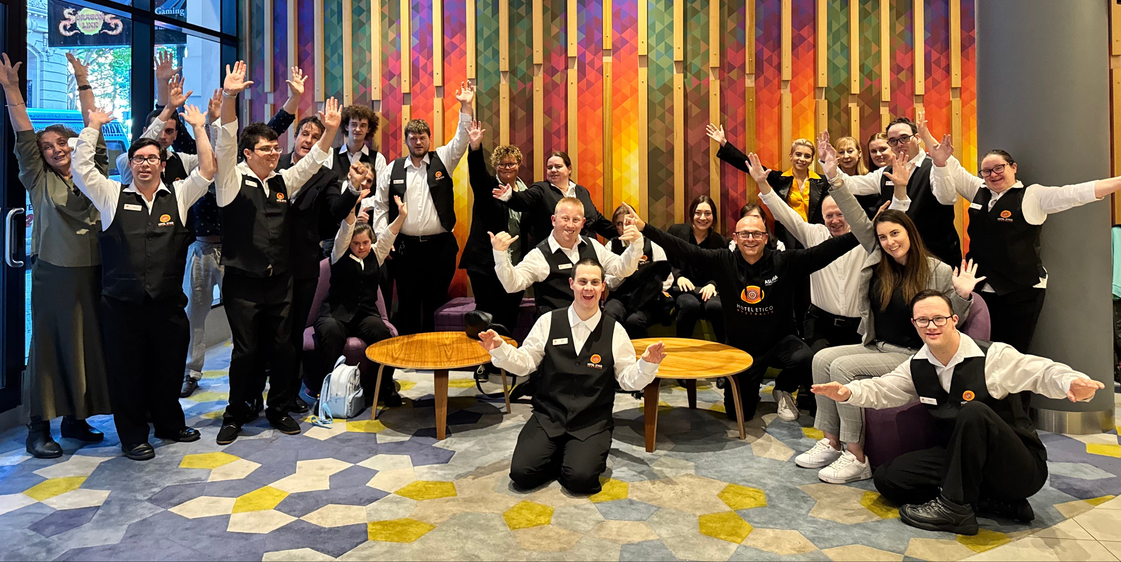 Group of people in uniforms posing together in a room with a colorful wall.